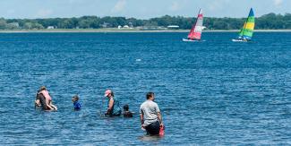 People swimming in the Ocean and sailboats