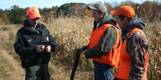 officer checking license for two pheasant hunters