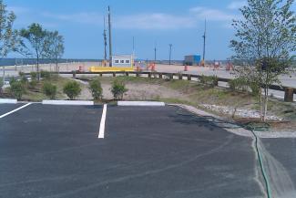 parking lot in front of a roped off gravel area with ocean visible behind it