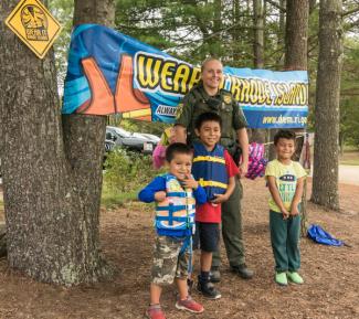 adult with three kids in front of a Wear It Rhode Island banner